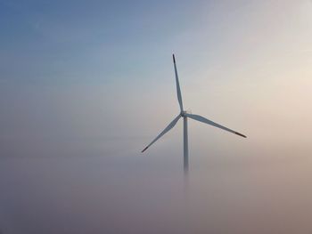 Low angle view of wind turbine against sky during sunset