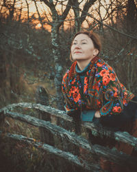 Portrait of young woman standing against trees