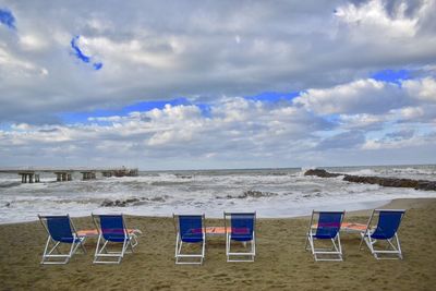 Chairs on beach against sky