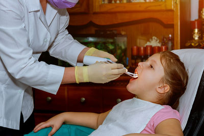 Midsection of dentist examining girl teeth in clinic