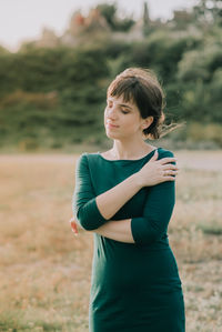 Young woman with eyes closed standing on field against plants