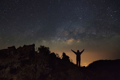 Silhouette man standing on field against sky at night