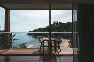 View of chairs against against sea seen through window