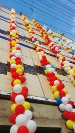 Low angle view of multi colored balloons against sky