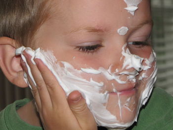 Close-up of boy applying shaving cream on face