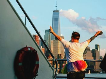 Rear view of man by railing against sky