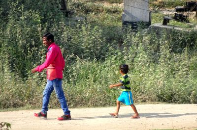 Full length of siblings playing on farm