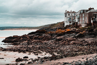 Rocks on beach by sea against sky