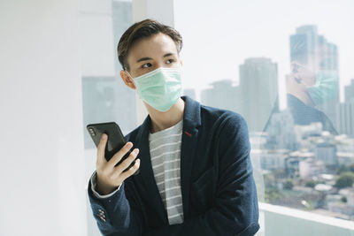 Portrait of man holding mobile phone standing in city