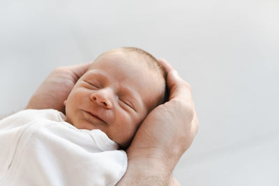 Newborn baby boy smiling lying on male father hands 