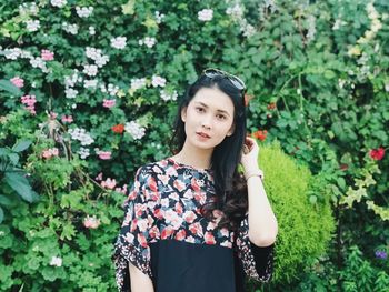 Portrait of young woman standing against plants