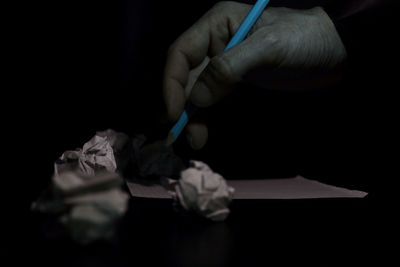 Close-up of man holding paper against black background