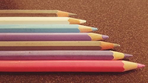 Close-up of colored pencils arranged in row on table