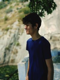 Young man looking away while standing outdoors