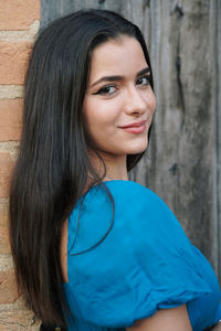 Portrait of young woman standing against wall