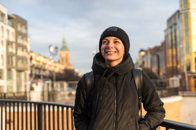 Smiling young woman traveling with backpack. happy female walking on the city street.