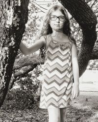 Portrait of teenage girl standing against tree