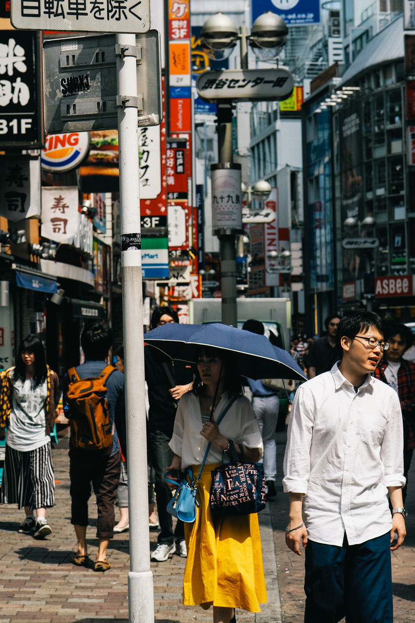 real people, men, walking, city, street, outdoors, large group of people, building exterior, architecture, women, built structure, city life, standing, road, lifestyles, day, adult, people