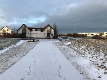 Houses by road against sky during winter