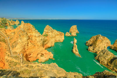 Panoramic view of rocks and sea against clear blue sky
