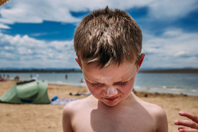 Close up of young boy at the beach with sunscreen on nose