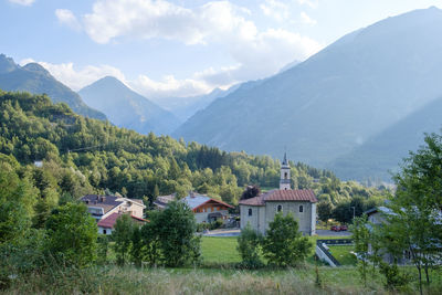 Houses by trees and mountains against sky