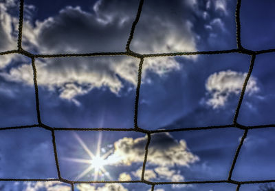 Low angle view of fence against cloudy sky