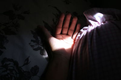 Close-up of person hand on bed