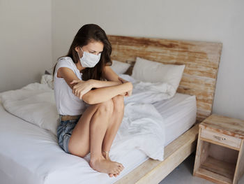 Young woman sitting on bed at home