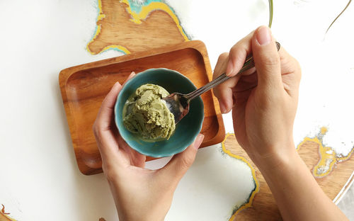 Cropped hand of woman having ice cream over table