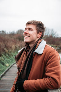 Smiling young man looking away against sky