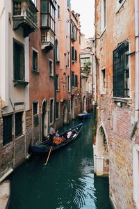 High angle view of people standing in gondola on canal amidst buildings