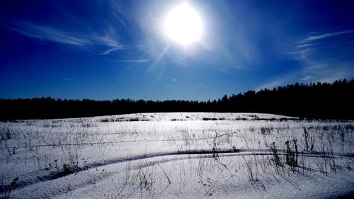 Scenic view of snow covered landscape against bright sun