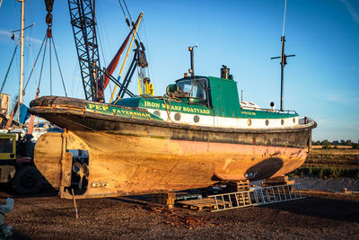 Old boat moored on shore against sky