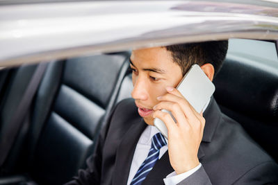 Close-up of businessman talking on phone while traveling in car