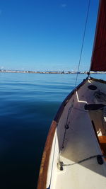 Sailboat sailing in sea against clear blue sky