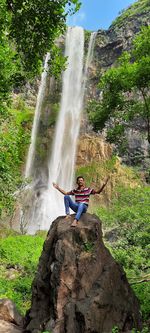 Rear view of man standing against waterfall