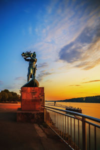 Statue by sea against sky during sunset