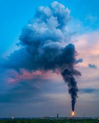 Smoke emitting from chimney against cloudy sky