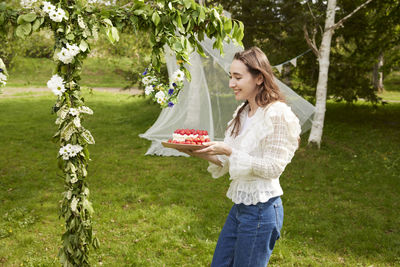 Woman carrying cake outdoors