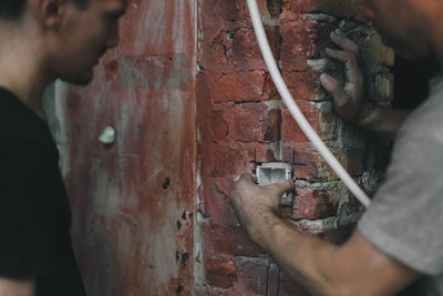 Two young man installs a socket in the wall.