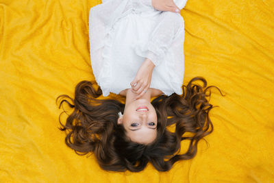 Top view of a happy white girl with a charming snow-white smile on a yellow background