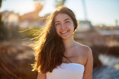 Portrait of smiling young woman against sky