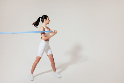 Full length of woman exercising against white background