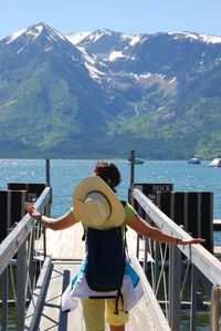 Rear view of woman walking on pier against mountains