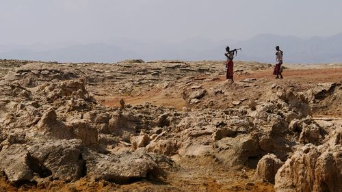 People on rock against sky