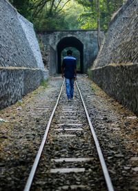Rear view of woman walking on railroad track