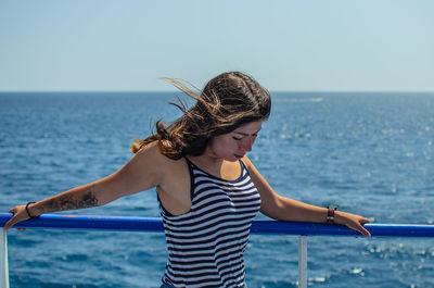 Woman standing by sea against sky