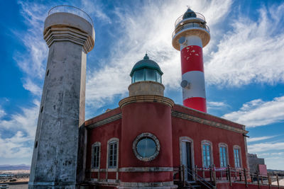 Low angle view of lighthouse by building against sky