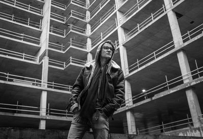 Low angle view of man looking away while standing against incomplete building